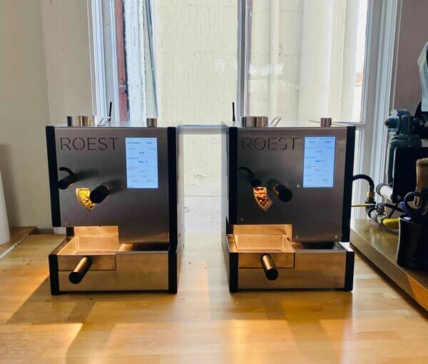 Two Roest sample roasters sit next to each other on a wooden counter.
